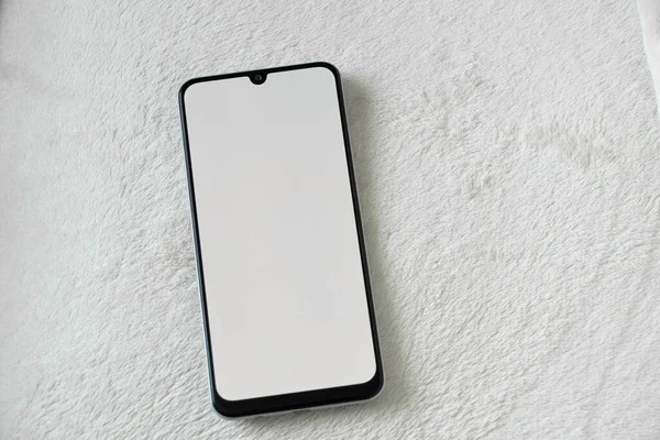 phone with a white screen lies on a white soft background close-up