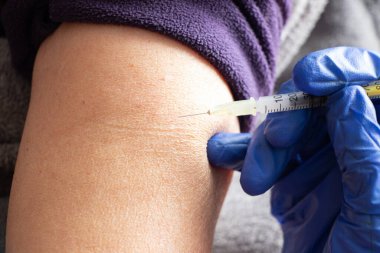 Yaşlı bir kadının elinde aşı olan bir iğne 2021 salgını sırasında kitlesel aşı.