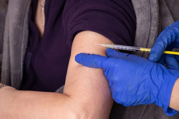an injection with a vaccine in the hand of an elderly woman, mass vaccination during the 2021 pandemic