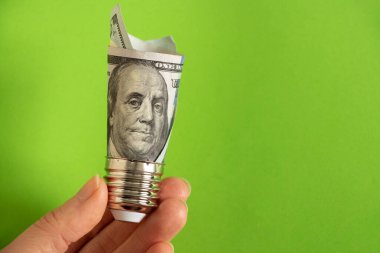 100 dolarlık banknotu olan lamba tutacağı yeşil arka plandaki bir kadının elinde vidaladı. Elektriğin fiyatı...