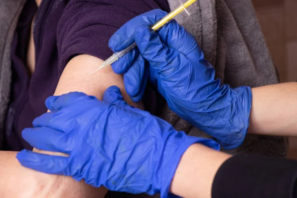an injection with a vaccine in the hand of an elderly woman, mass vaccination during the 2021 pandemic