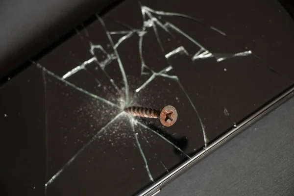 a screw is screwed into the screen of a touch-sensitive black mobile phone, a broken phone