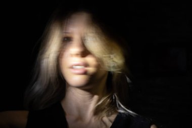 Bir kızın yüzü karanlıkta hareketli uzun bir pozda