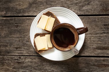 Mutfakta kahvaltı için ahşap bir masada peynirli bir fincan kahve ve ekmek.