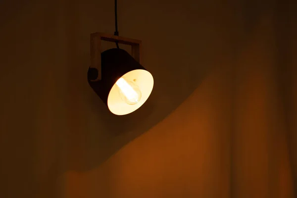 included electric light bulb on the background of dark curtains, lamp light