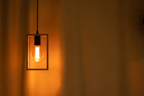 included electric light bulb on the background of dark curtains, lamp light