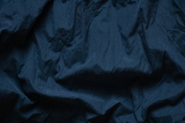 Koyu mavi kumaş arka planda yakın plan olarak buruşmuş