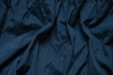 Koyu mavi kumaş arka planda yakın plan olarak buruşmuş