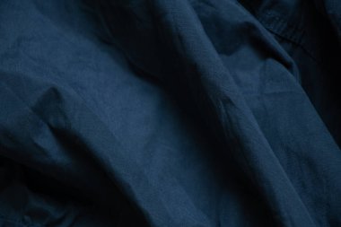 Koyu mavi kumaş arka planda yakın plan olarak buruşmuş