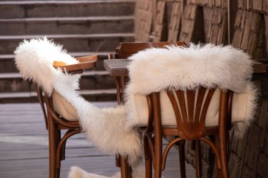 Boş bir odada beyaz kürk battaniyeli ahşap sandalyeler, ahşap mobilyalar, yatakhane dekorasyonu.