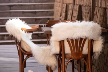 Boş bir odada beyaz kürk battaniyeli ahşap sandalyeler, ahşap mobilyalar, yatakhane dekorasyonu.