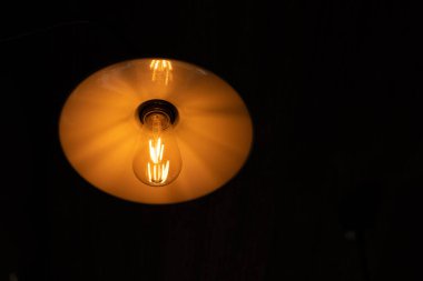 Koyu perdelerin arka planında elektrik ampulü ve lamba ışığı vardı.