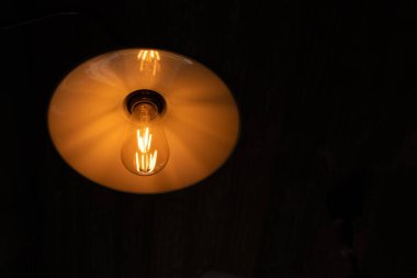 Koyu perdelerin arka planında elektrik ampulü ve lamba ışığı vardı.