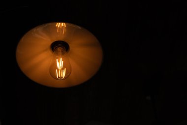 Koyu perdelerin arka planında elektrik ampulü ve lamba ışığı vardı.