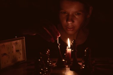 Mum ışığında satranç oynayan, satranç oynayan bir kız.