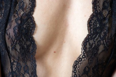 Siyah dantelli iç çamaşırlı genç kız yatak odasındaki kırmızı koltukta oturuyor.