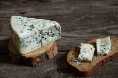 Ahşap bir masanın üzerinde bir parça mavi peynir.