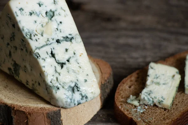 Ahşap bir masanın üzerinde bir parça mavi peynir.