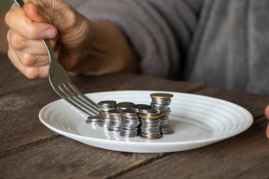 Eski ahşap bir masada beyaz bir tabakta bir yığın bozuk para ve yaşlı kadın elleri evdeki mutfağa bir tabak döktü.