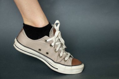 Stüdyoda koyu mavi arka planda tekstil ayakkabısı giyen kadın bacağı.