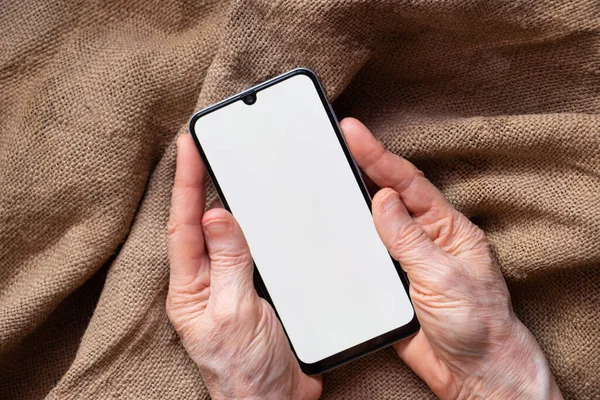 phone with a white screen in the hands of an elderly woman on the table close-up, white screen on the phone
