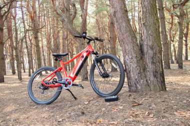 Ukraine Dnipro 05.04.2021 - a red electric bike is recharged in a forest in a park, new technologies, an electric bike