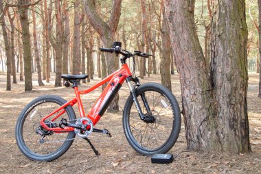 Ukraine Dnipro 05.04.2021 - a red electric bike is recharged in a forest in a park, new technologies, an electric bike