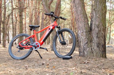 Ukraine Dnipro 05.04.2021 - a red electric bike is recharged in a forest in a park, new technologies, an electric bike