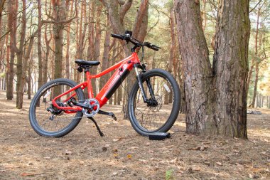 Ukraine Dnipro 05.04.2021 - a red electric bike is recharged in a forest in a park, new technologies, an electric bike