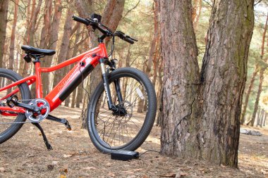 Ukraine Dnipro 05.04.2021 - a red electric bike is recharged in a forest in a park, new technologies, an electric bike