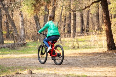 Dnipro şehrinde, Ukrayna 'nın bahar ormanlarında elektrikli bisiklet süren bir kız.