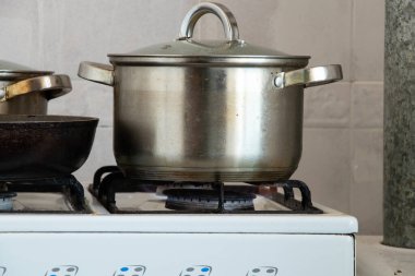 Tencereler evdeki mutfakta gaz ocağında, ocakta yemek pişiriyorlar.