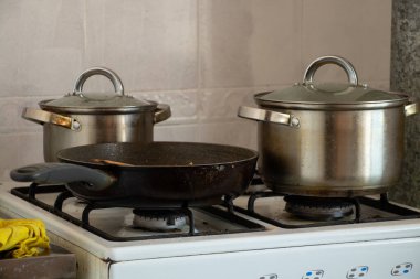 Tencereler evdeki mutfakta gaz ocağında, ocakta yemek pişiriyorlar.