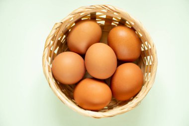 Sarı tavuk yumurtaları hasır bir sepetin içinde yakın plan çekimde duruyor.