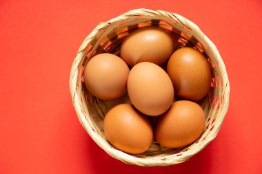 Sarı tavuk yumurtaları hasır bir sepetin içinde yakın plan çekimde duruyor.