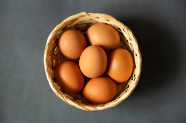 Sarı tavuk yumurtaları hasır bir sepetin içinde yakın plan çekimde duruyor.