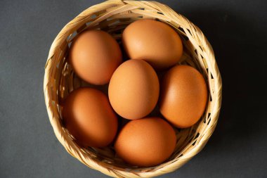 Sarı tavuk yumurtaları hasır bir sepetin içinde yakın plan çekimde duruyor.