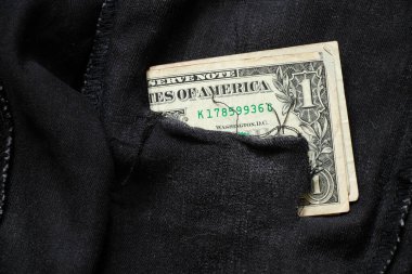 Dolar banknotları yakın plan siyah kot pantolonlara, dolarlara yatar.