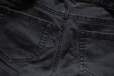 Arka plan olarak giyilen siyah kot pantolon. Yakın plan, kot pantolon modası.