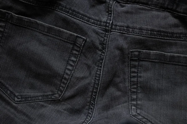 Arka plan olarak giyilen siyah kot pantolon. Yakın plan, kot pantolon modası.