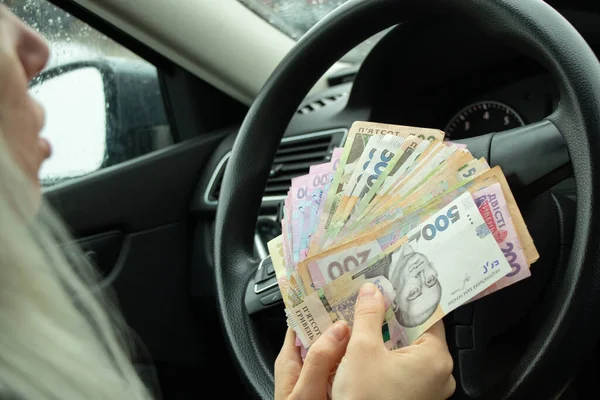 Ukrainian money 200 and 500 is held by a girl in the hands of her own car, money for a car