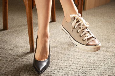 Spor ayakkabı ve klasik yüksek topuklu ayakkabılar. Kızın ayaklarında siyah ayakkabılar. Ayakkabı seçimi, ne giyeceği.