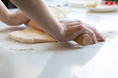 Kadın elleri hamur yoğurur mutfakta beyaz bir masada, hamur