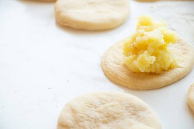 Evde patatesli turta yapma süreci mutfakta beyaz bir masada, ev yapımı patates alışkanlığı.