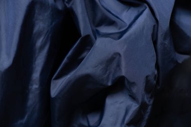 Koyu mavi kumaş arka planda yakın plan olarak buruşmuş