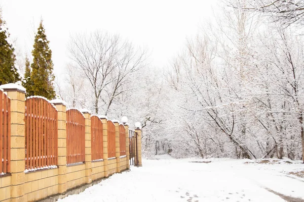 brick fence with gates on the background of a winter forest in the snow in Ukraine