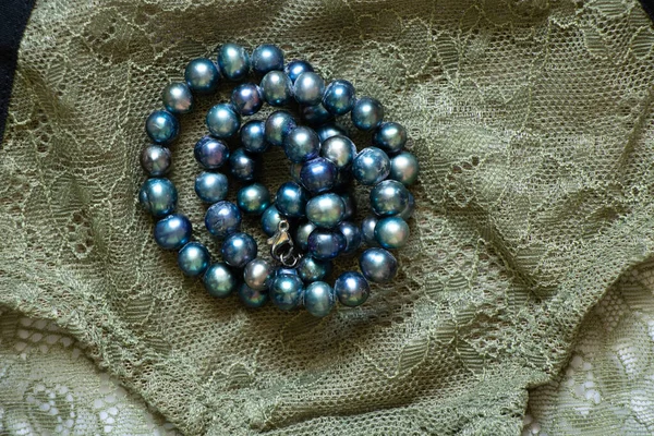 Blaue Perlen Liegen Auf Grüner Spitze Auf Weißem Hintergrund Schönheitsmode — Stockfoto