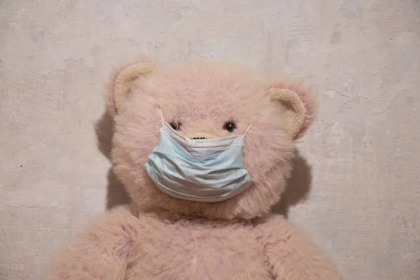 白い壁の背景の医療用マスクの赤ちゃんピンクのテディベア — ストック写真