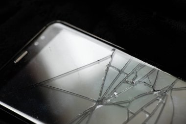 Siyah arka planda kırılmış telefon ekranı, bozuk telefon.