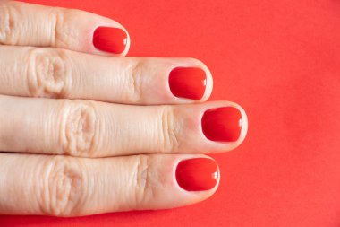 Kırmızı manikürlü kadın elleri izole edilmiş arka planda.